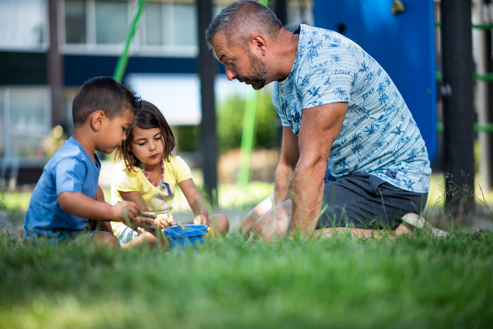 Vader en spelende kinderen in speeltuin