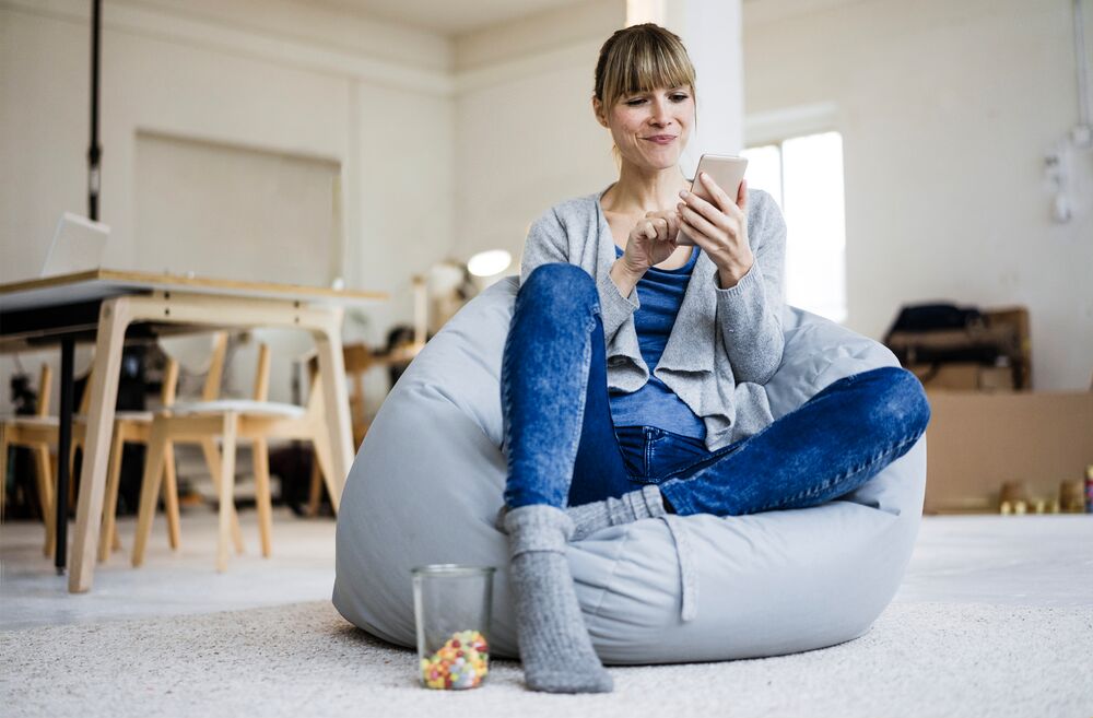 Vrouw zit op zitzak met telefoon