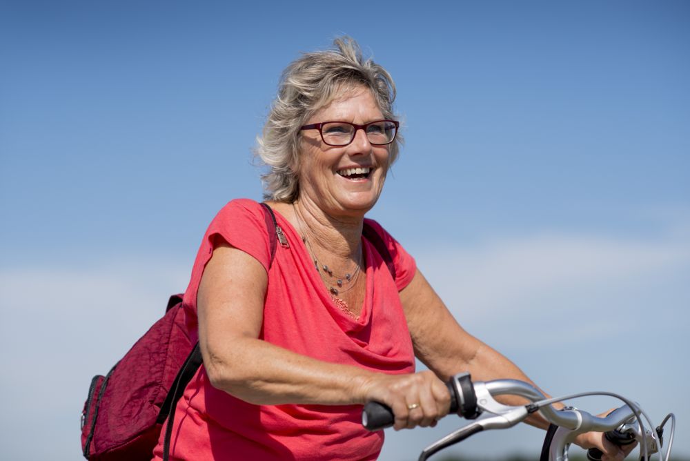 Vrouw lachend op de fiets met rood shirt