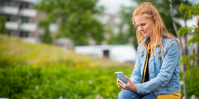 Vrouw op een bankje buiten met mobiel