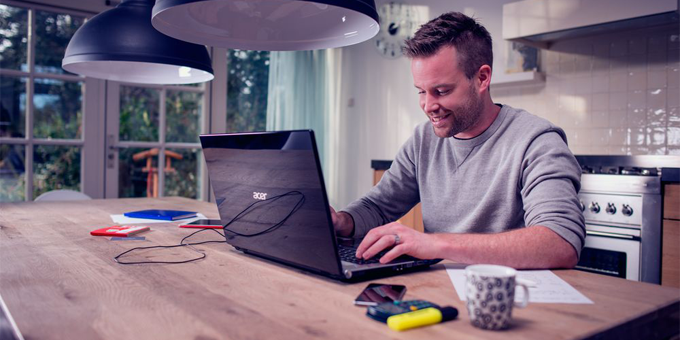 Man aan keukentafel met laptop